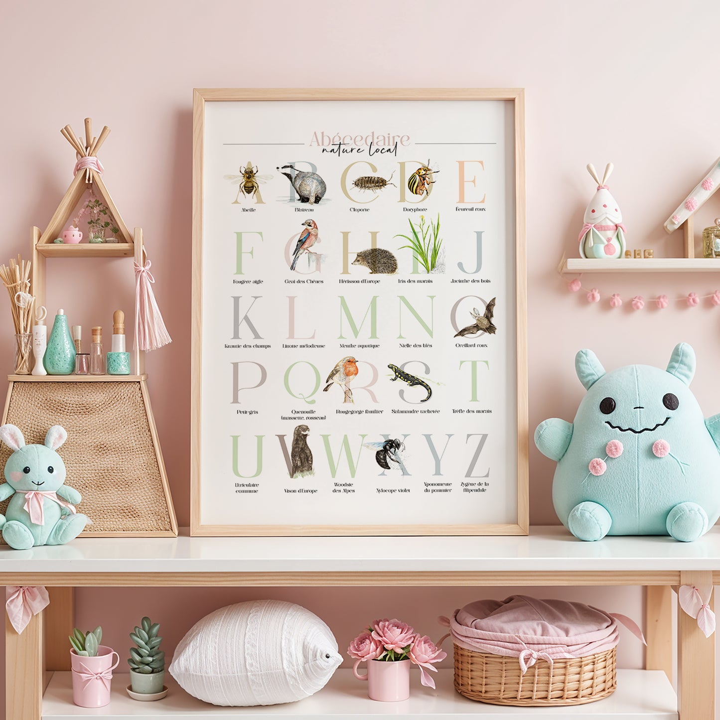 Illustration encadrée de l’abécédaire de la faune et de la flore, posée sur une étagère dans une chambre d’enfant, avec un fond rose pastel.